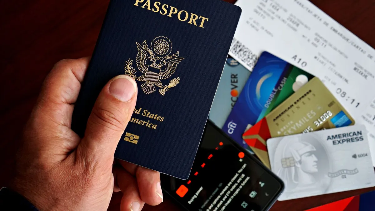 Mão segurando passaporte americano sobre documentos e cartões
