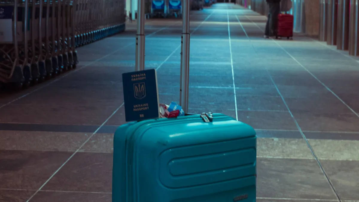 Mala azul e passaporte em aeroporto vazio, simbolizando a saída definitiva do Brasil para morar nos EUA