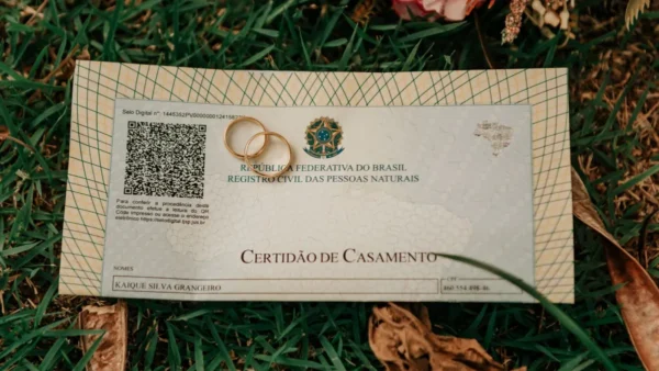 Certidão de casamento brasileira com alianças sobre a grama